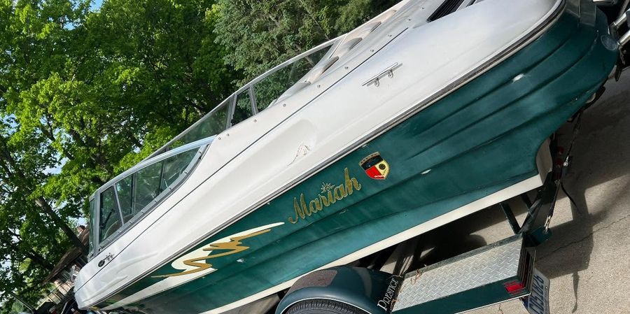 Green and white boat on a trailer with dull, chalky, oxidised gel coat before detailing