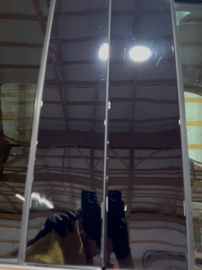 The same pillar trim after machine polishing, reflecting the workshop like a mirror